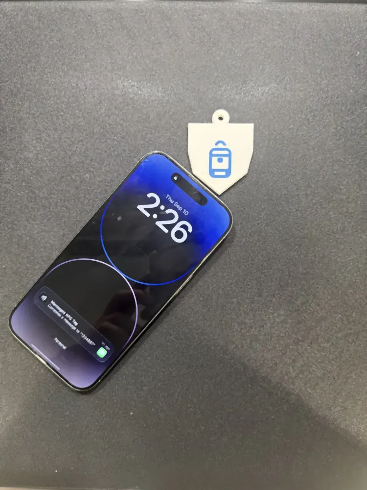 An iPhone lying next to a printed kids bag tag with the NFC notification on its lock screen