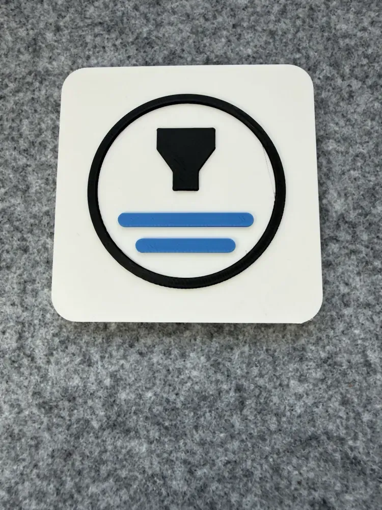 Square white logo plaque with a black and blue Formada3D mark raised on it, on grey felt