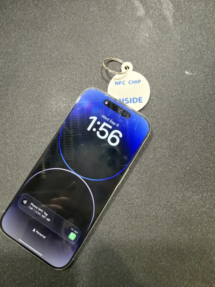 An iPhone resting on the BUDDY pet tag with the NFC call prompt showing on the lock screen