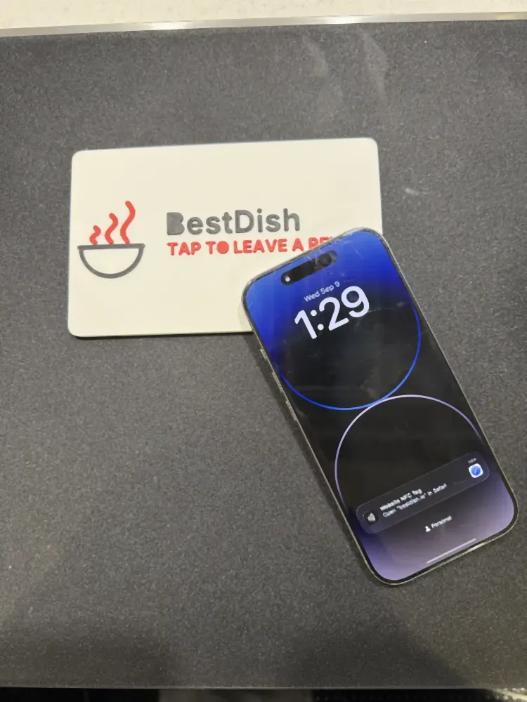 An iPhone being held on the review plaque, the NFC banner visible on its screen
