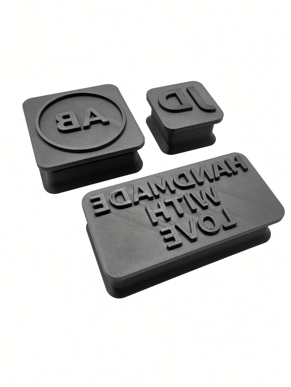 Three printed custom stamps — AB monogram, JD initials and HANDMADE WITH LOVE — angle view